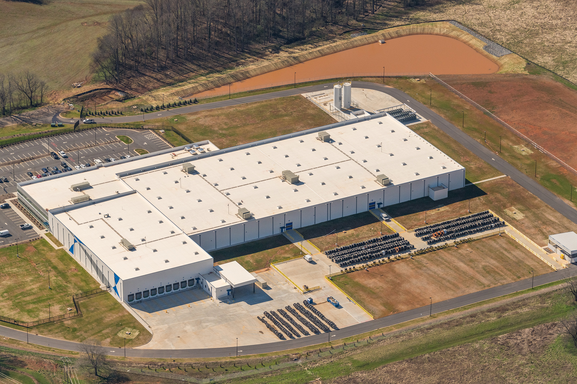 An aerial view of a large distribution warehouse, parking lots, and detention ponds
