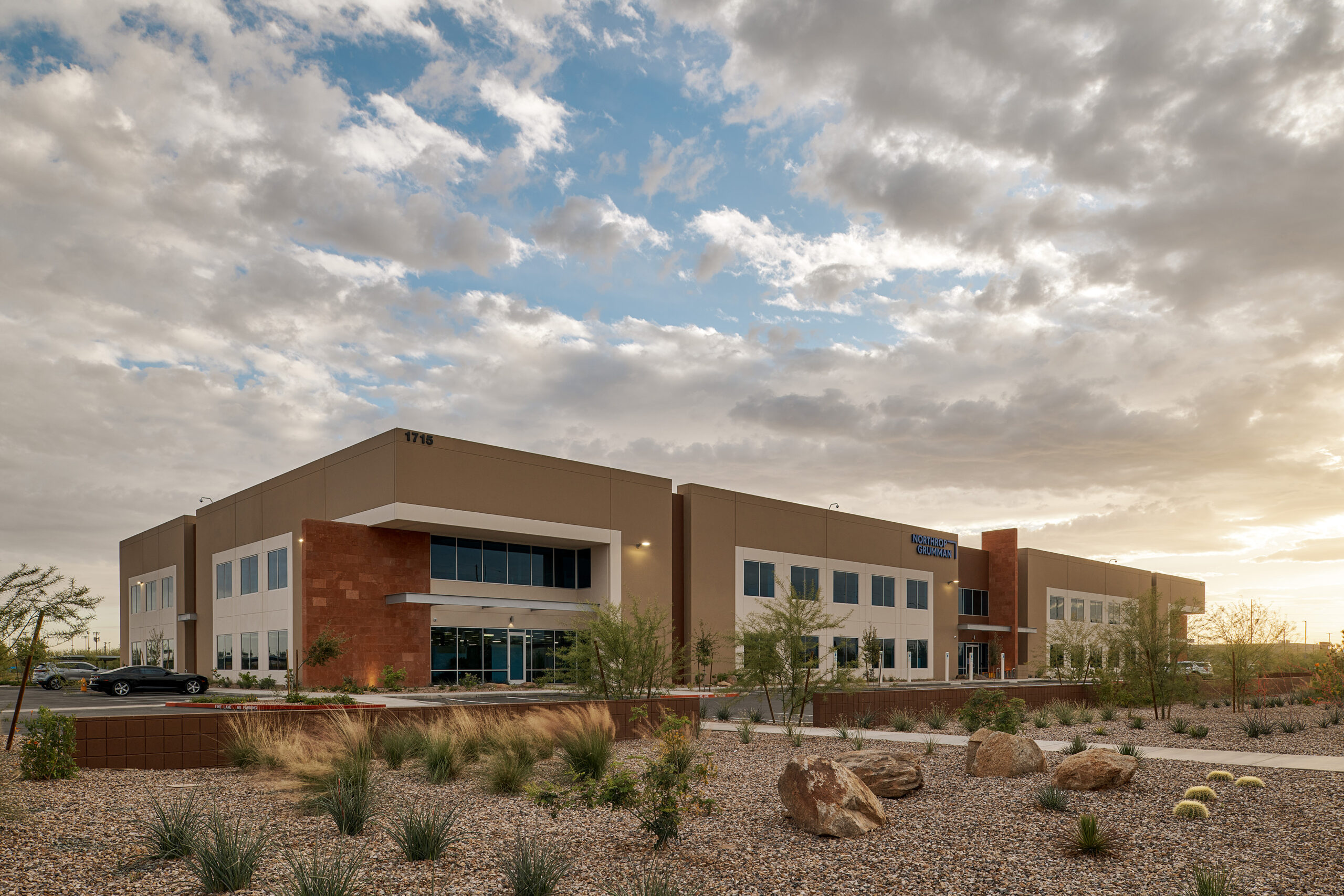 A two story office building in a desert setting at sunset