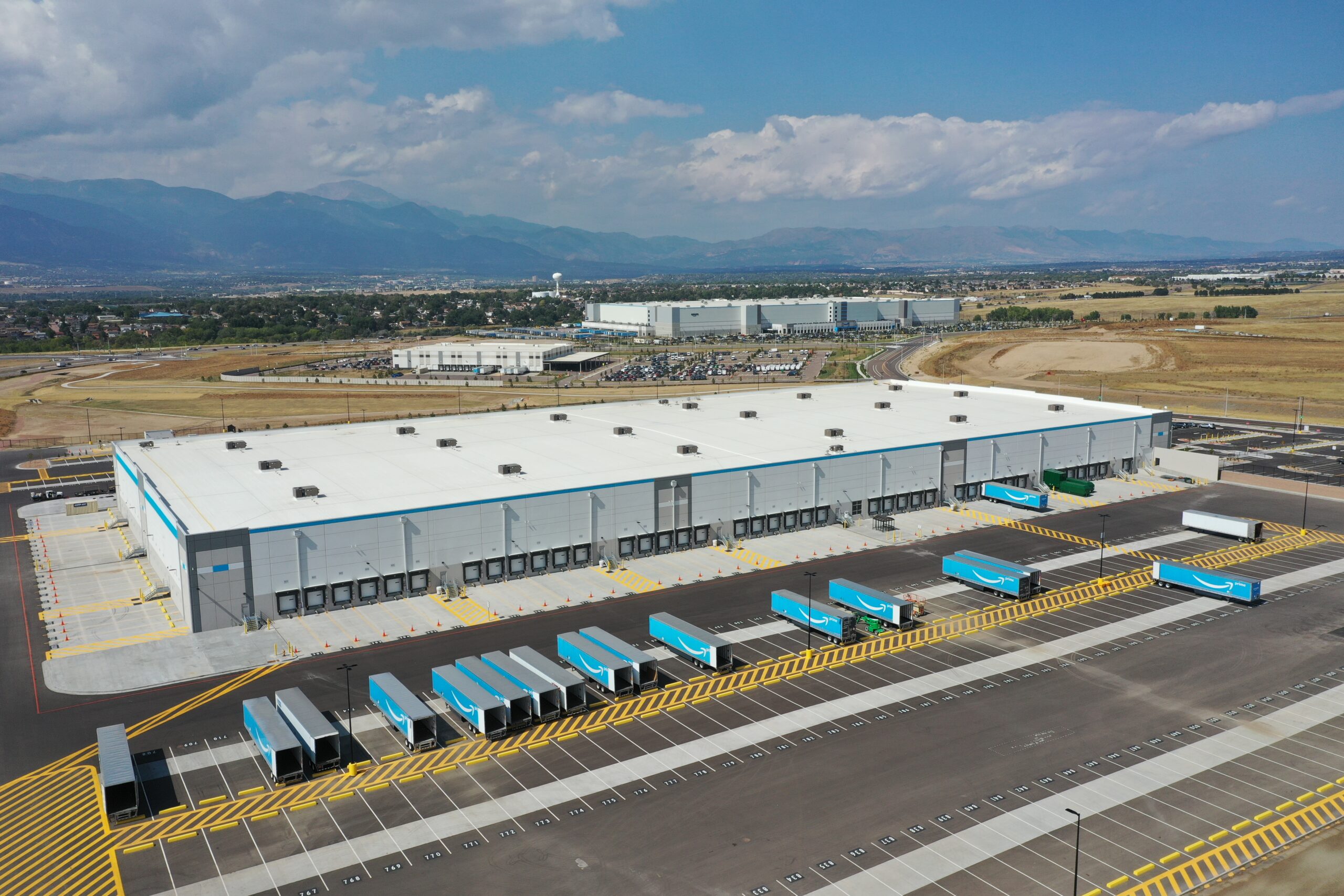 A large distribution warehouse with multiple trailers parked in a mountainous area