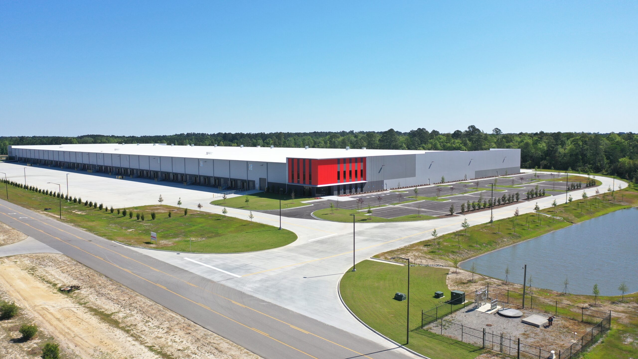 A large distribution center with many dock doors, including entrance road and detention pond